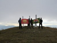 Соратники с флагами у памятника на вершине горы